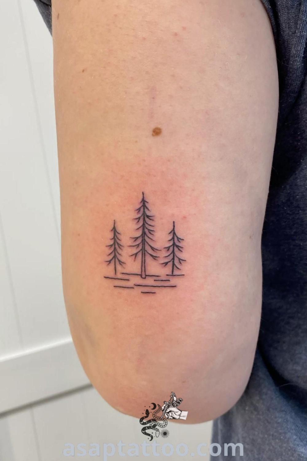 Dainty small forest tattoo design featuring a minimalist single line pine tree, perfect for women seeking small tree tattoo ideas. Discover elegant tattoos with meaning at asaptattoo.com.
