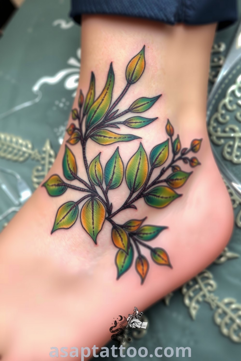 Mixed-media plant tattoo wrapping around the ankle with vibrant greens and earthy browns, intricate linework, and smooth gradients. A gorgeous tattoo idea you must see to believe. asaptattoo.com