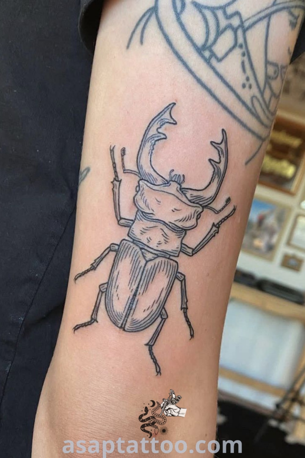 Black and grey beetle tattoo with antlers on the left arm, showcasing whimsical design elements. An amazing choice for matching beetle tattoos and knee tattoos unique in style. Explore more ideas at asaptattoo.com.