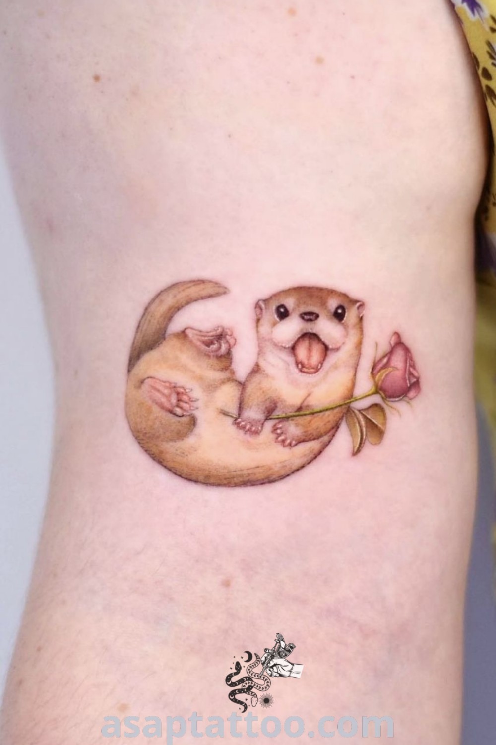 A cute otter tattoo with a flower on its leg, perfect for women seeking animal tattoos with meaning. An inspiring piece to decorate your body with, discover more amazing designs at asaptattoo.com.