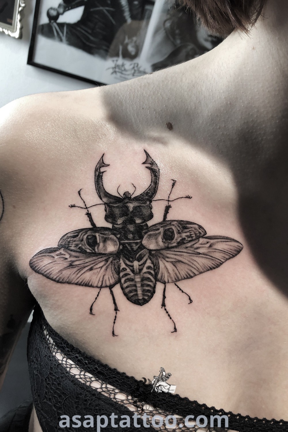 A woman with a bug and antelope tattoo on her chest, showcasing elegant black work design. A breathtaking example of tattoo artistry that inspires you to explore unique ink ideas. Find more inspiration at asaptattoo.com.