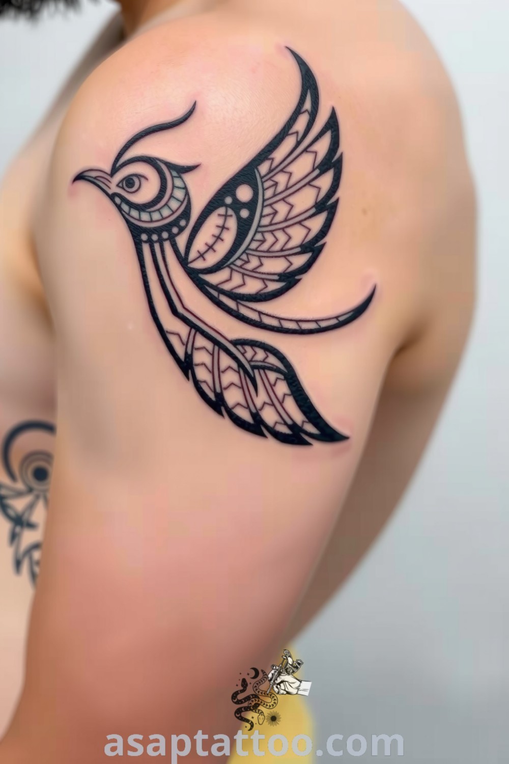 Tribal bird tattoo on the shoulder with bold black lines and geometric patterns, symbolizing freedom and personal significance. An amazing tattoo idea you must see. asaptattoo.com