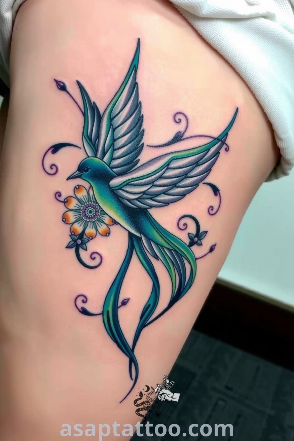 Art Nouveau bird tattoo in deep blues and greens with fluid lines and floral elements, creating an elegant and inspiring design. A gorgeous tattoo idea you must see to believe. asaptattoo.com
