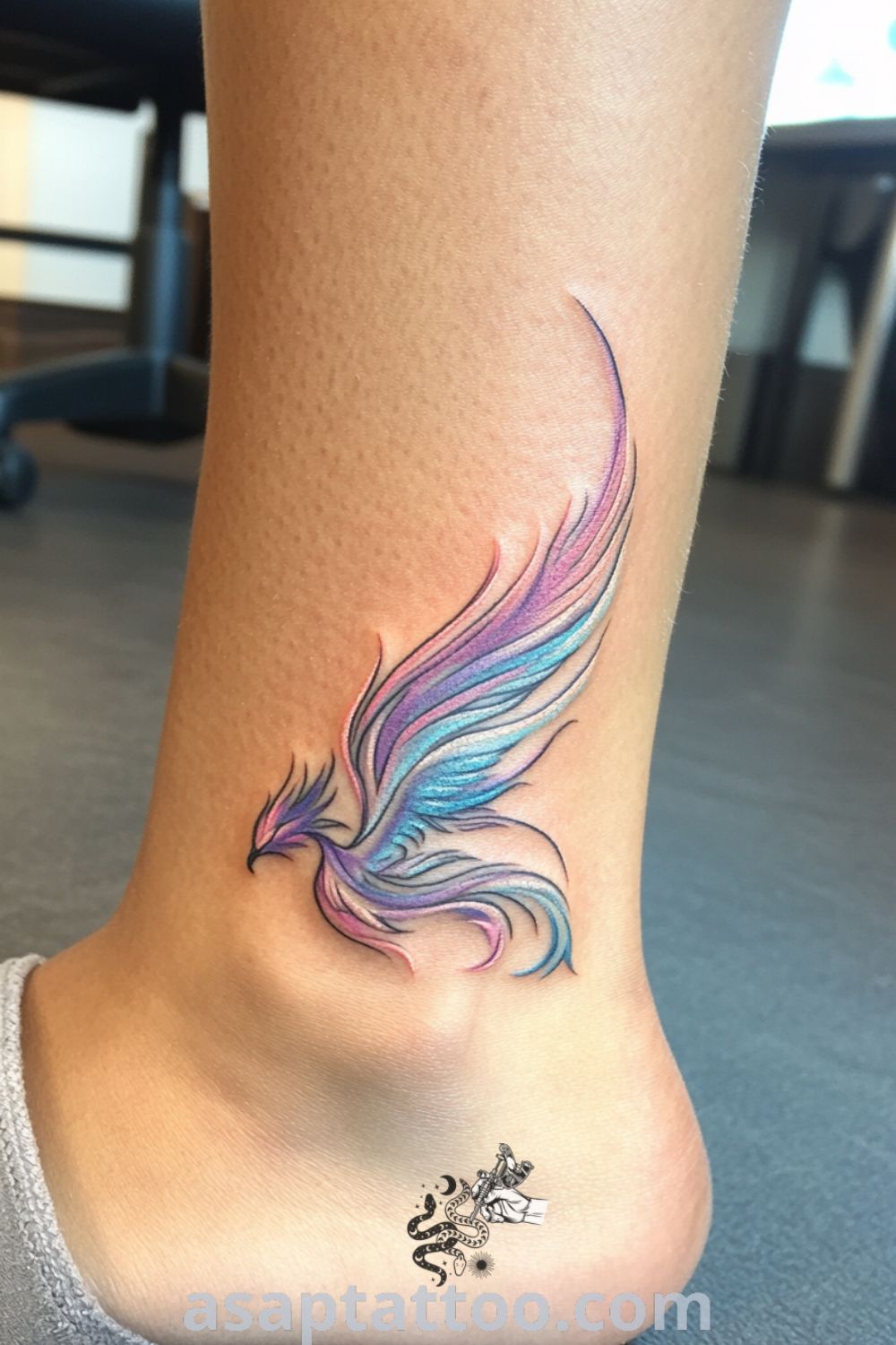 Pastel phoenix tattoo on the ankle featuring soft pink, blue, and lavender colors with intricate linework and shading. A gorgeous tattoo that symbolizes renewal and transformation, perfect for inspiring designs you must see. asaptattoo.com