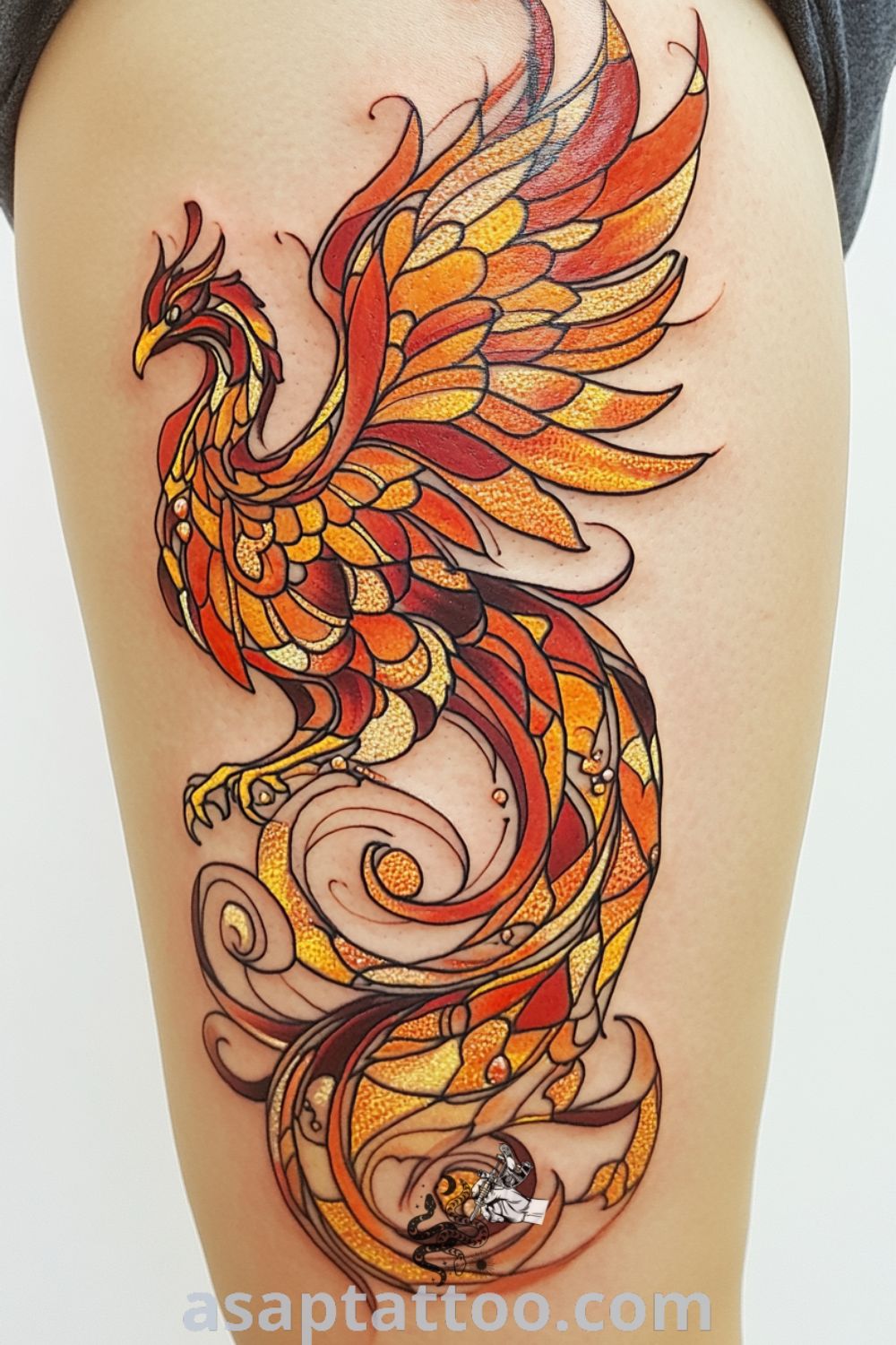Stained glass phoenix tattoo featuring vibrant red, orange, and yellow colors with intricate linework that adds depth. A stunning tattoo idea that symbolizes rebirth and will inspire you to get inked. asaptattoo.com