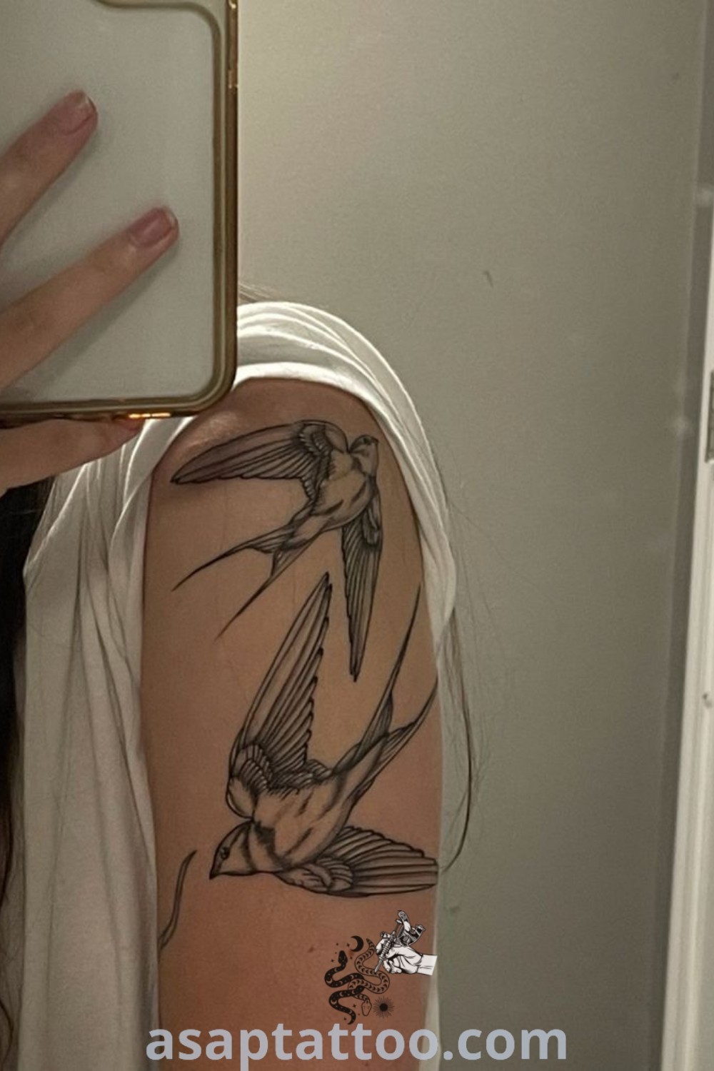 A woman with a bird swallow tattoo on her arm holding a cell phone, showcasing elegant female arm tattoos patchwork. This stunning ink art combines intricate designs perfect for anyone seeking tattoos with meaning and inspiration. Explore ideas to inspire you at asaptattoo.com.