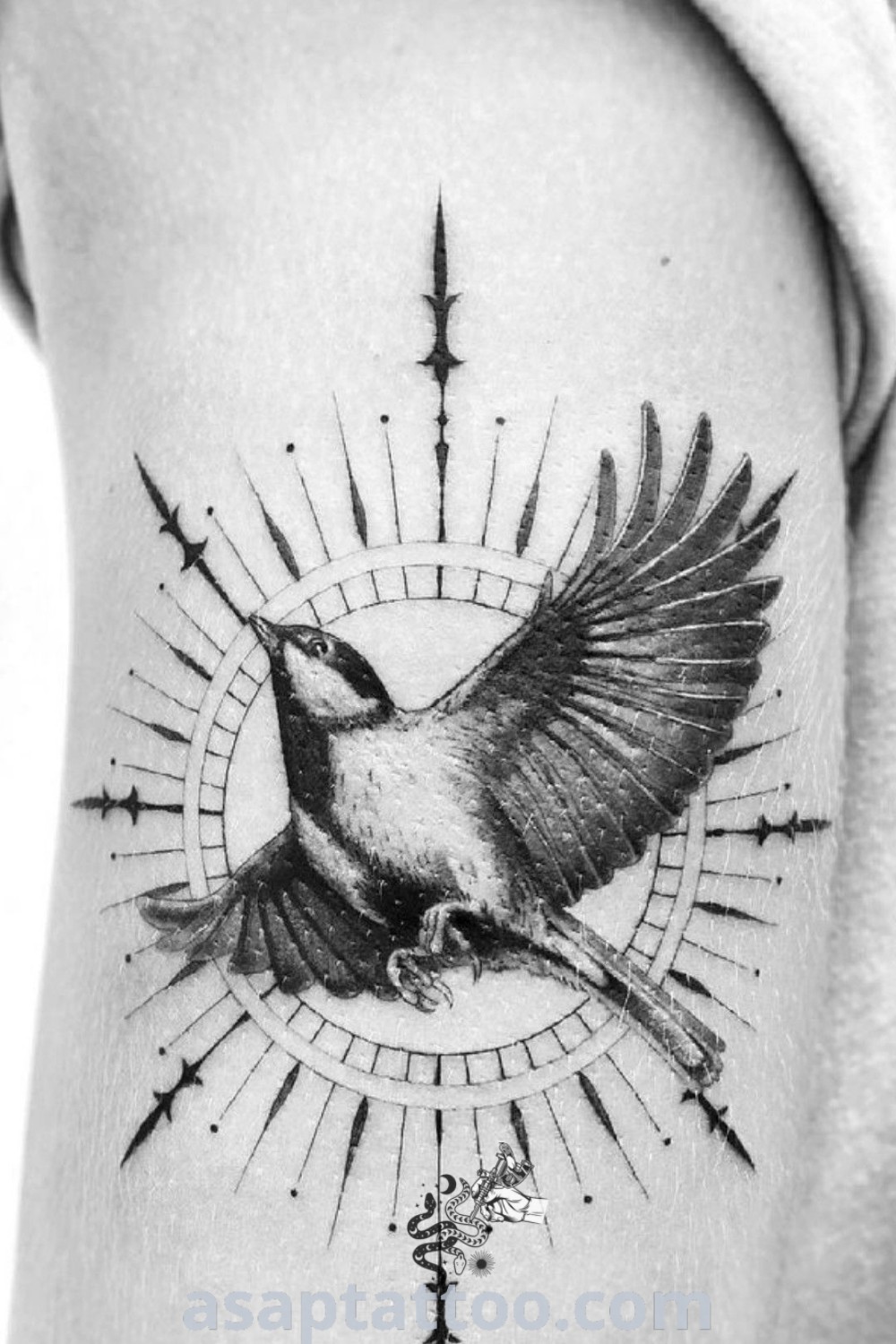 Black and white photo of a bird with halo tattoo, featuring traditional ink style. This masculine tattoo design presents amazing artistry that will inspire you to get inked. Explore more stunning ideas at asaptattoo.com.
