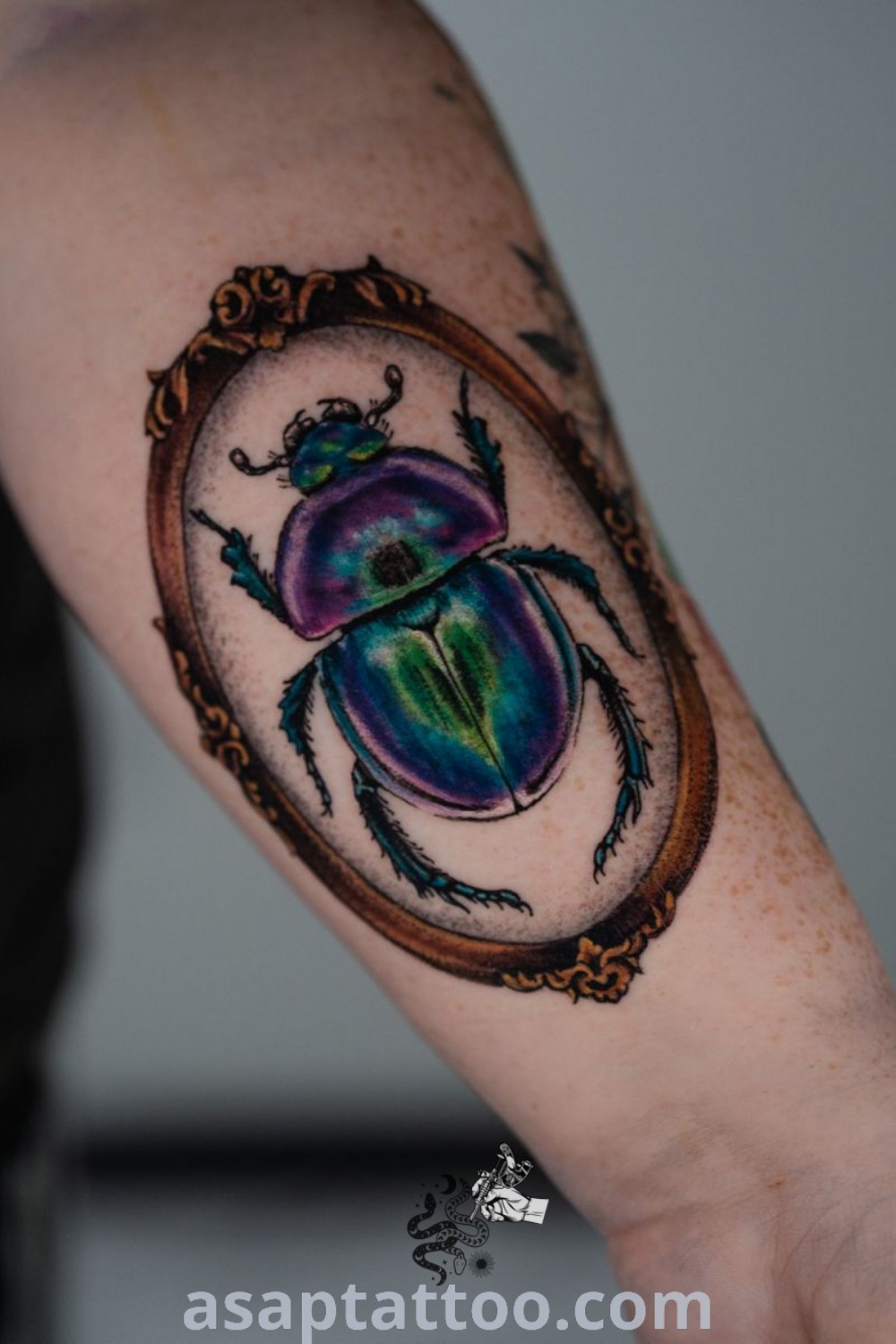 Colorful beetle tattoo on the right arm and shoulder, featuring an oval frame and detailed design. A beautiful choice for those looking for amazing tattoo ideas such as matching beetle tattoos. Discover more inspirations at asaptattoo.com.