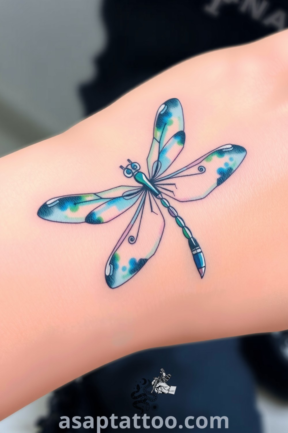 Watercolor dragonfly tattoo with vibrant blue and green wings, featuring delicate linework and soft gradients. A gorgeous tattoo that inspires and enhances your body art collection. asaptattoo.com
