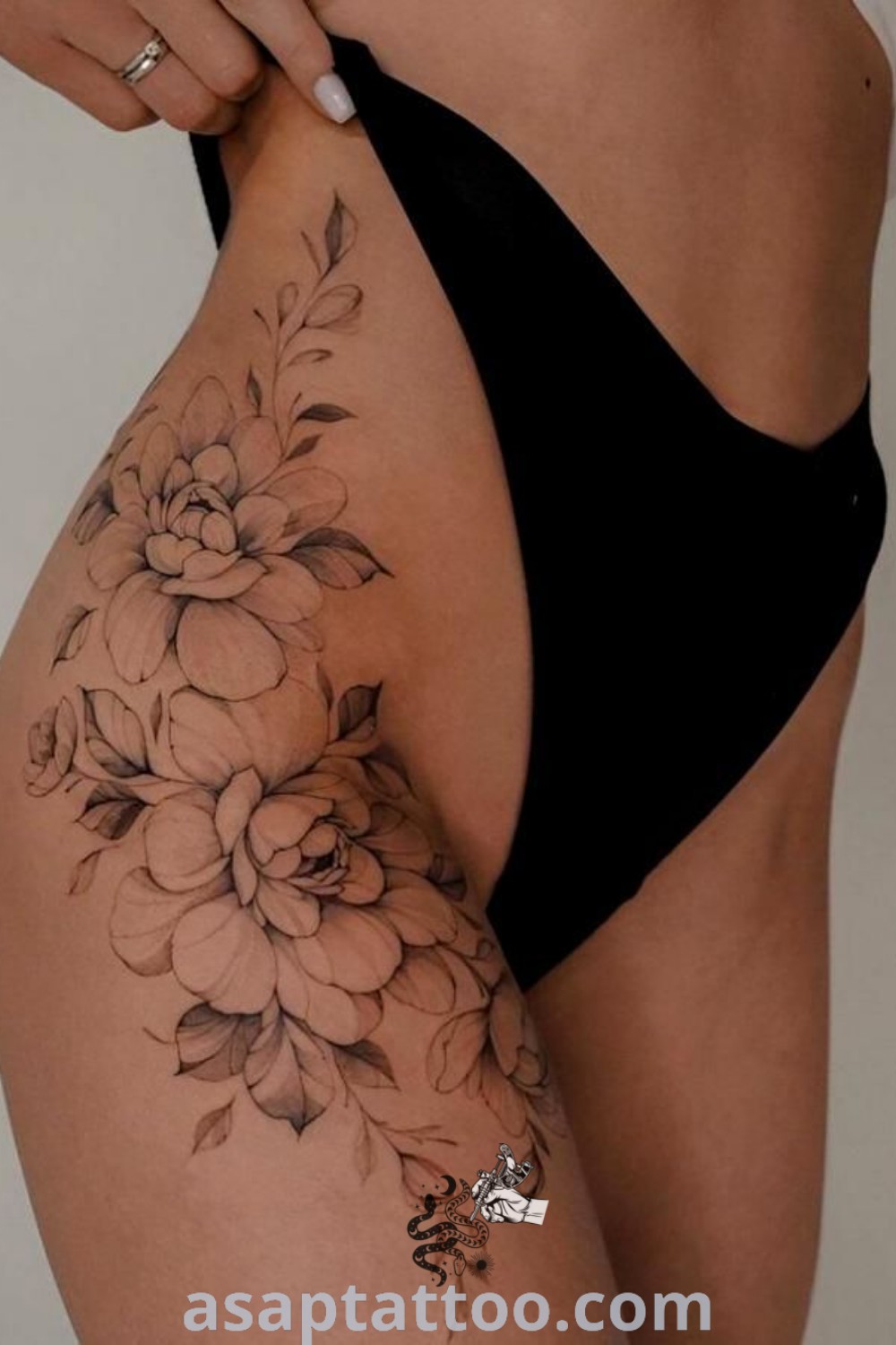 Floral thigh tattoo featuring flowers on the stomach and bottom half of panties, combined with feminine bracelet designs. A gorgeous choice for women looking for inspiring tattoos with meaning. Explore more at asaptattoo.com.