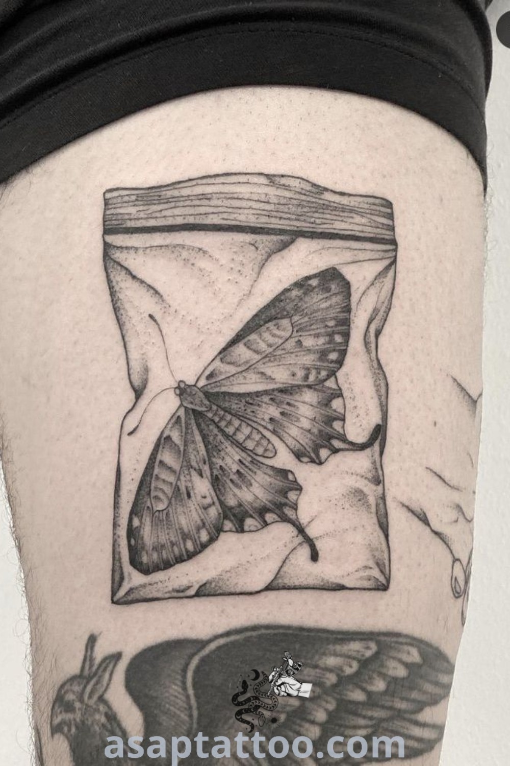 Black and white tattoo of a butterfly in a jar on a woman