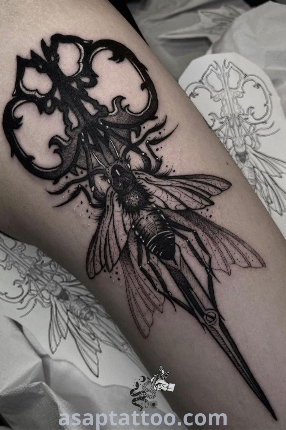 Black and white tattoo design on the leg featuring the phrase "Goth Word Tattoo" with intricate gothic style elements, scissors included. A captivating option for fans of gothic tattoos and elegant body art. Discover more at asaptattoo.com.