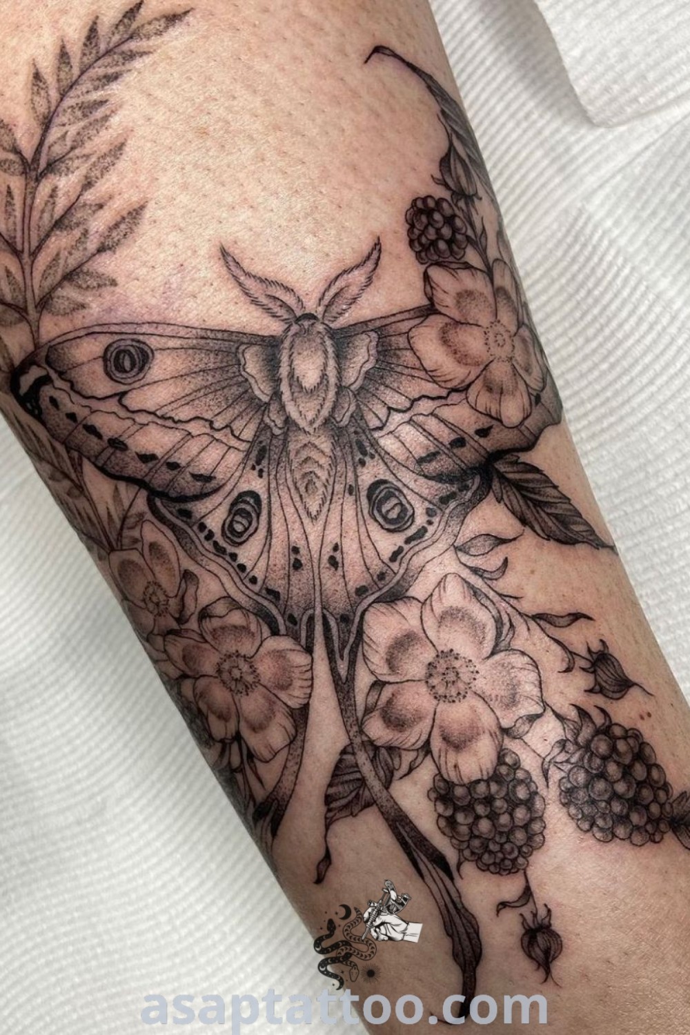Luna Moth upper arm tattoo featuring flowers and leaves in black and grey ink. An elegant design that showcases amazing insect half sleeve tattoos. Explore captivating moth tattoo ideas at asaptattoo.com.