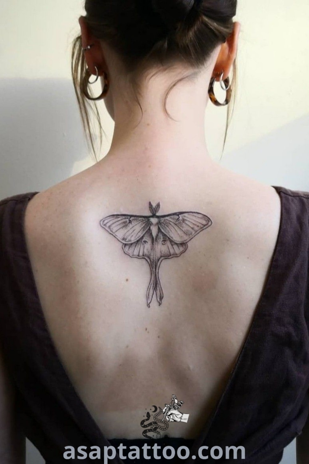 Delicate moth tattoo on the back of a woman