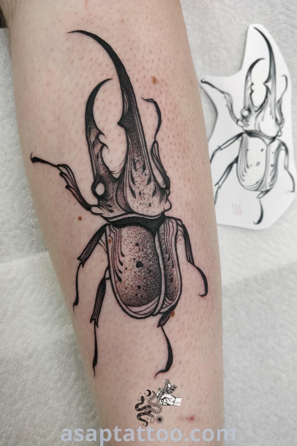 Black and white beetle tattoo on the leg featuring intricate dot work, perfect for insect tattoo enthusiasts. A stylish homage to nature available at asaptattoo.com.