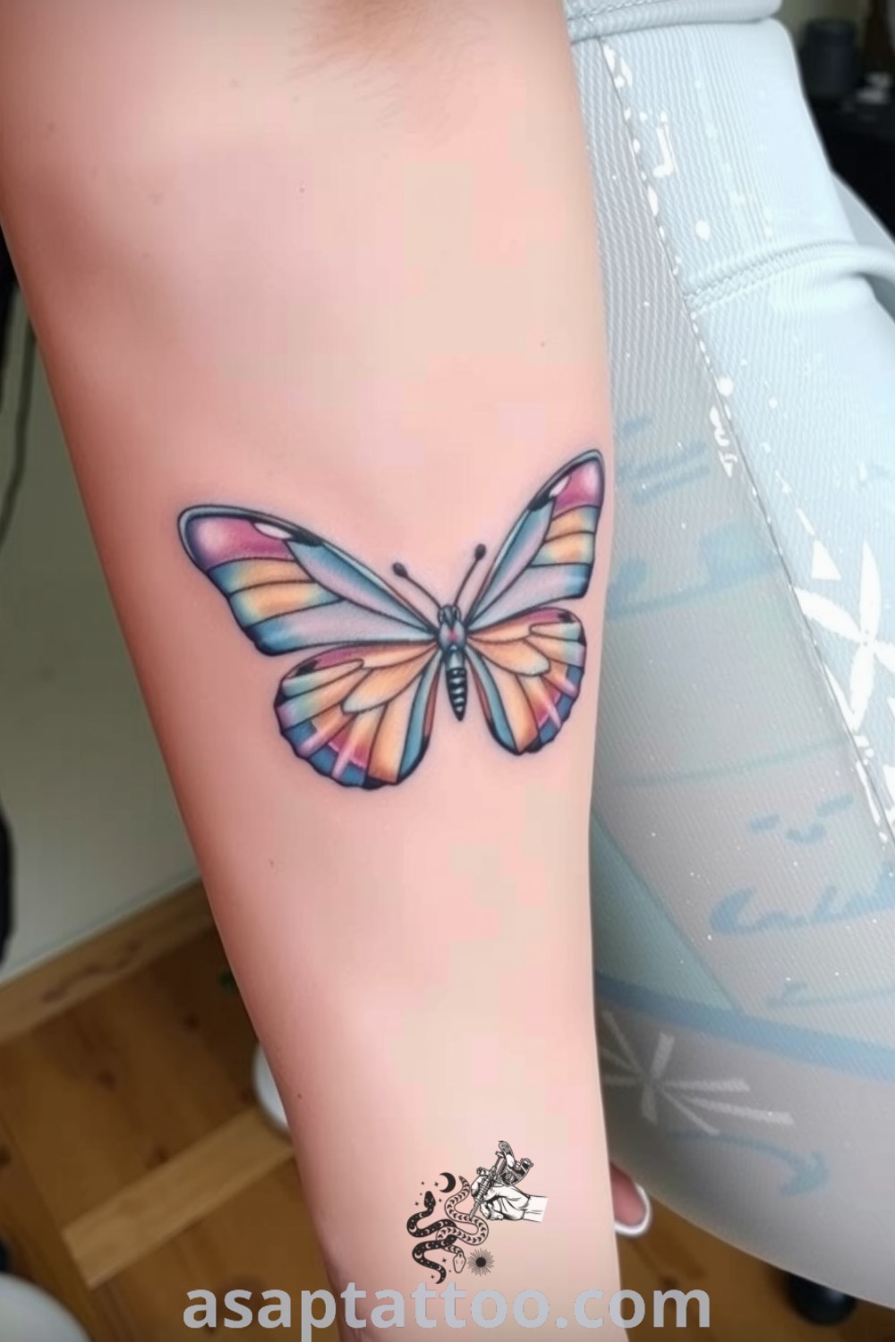 Pastel butterfly tattoo on the inner arm with lavender, sky blue, and peach colors, showcasing delicate linework and soft gradients. A gorgeous tattoo idea you must see to believe. asaptattoo.com