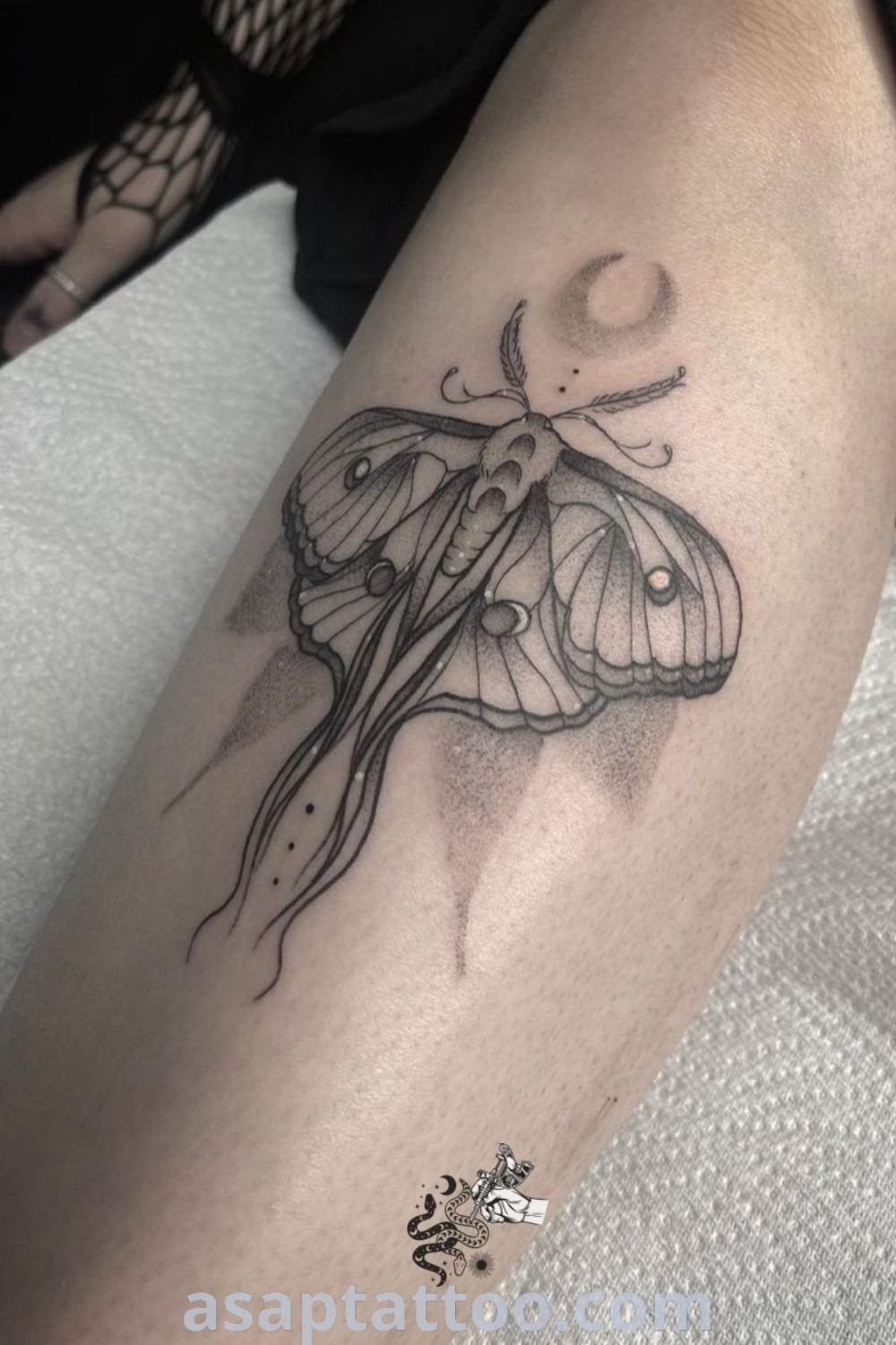 A black and white photo of a lunar moth tattoo on the arm, showcasing gothic art style and elegant design. Explore amazing tattoo ideas that inspire at asaptattoo.com.