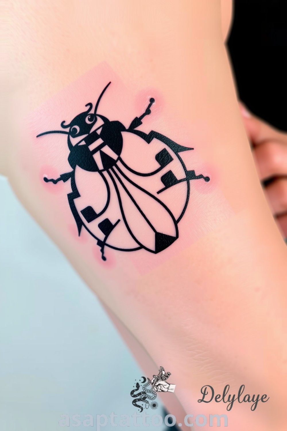 Geometric ladybug tattoo on bicep with intricate designs of black outlines and gray shading, showcasing a unique and elegant style. This tattoo idea is amazing and you must see it to believe. asaptattoo.com