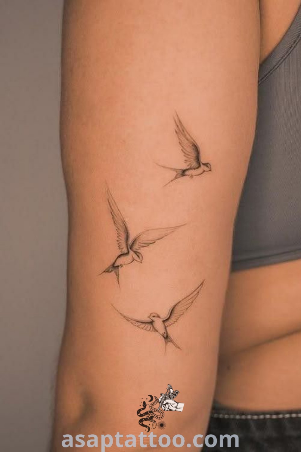 A woman’s arm displaying a fine line tattoo with three small birds, showcasing mother bird and swallow bird designs. Perfect inspiration for tattoos with meaning. Discover more amazing tattoo ideas at asaptattoo.com.