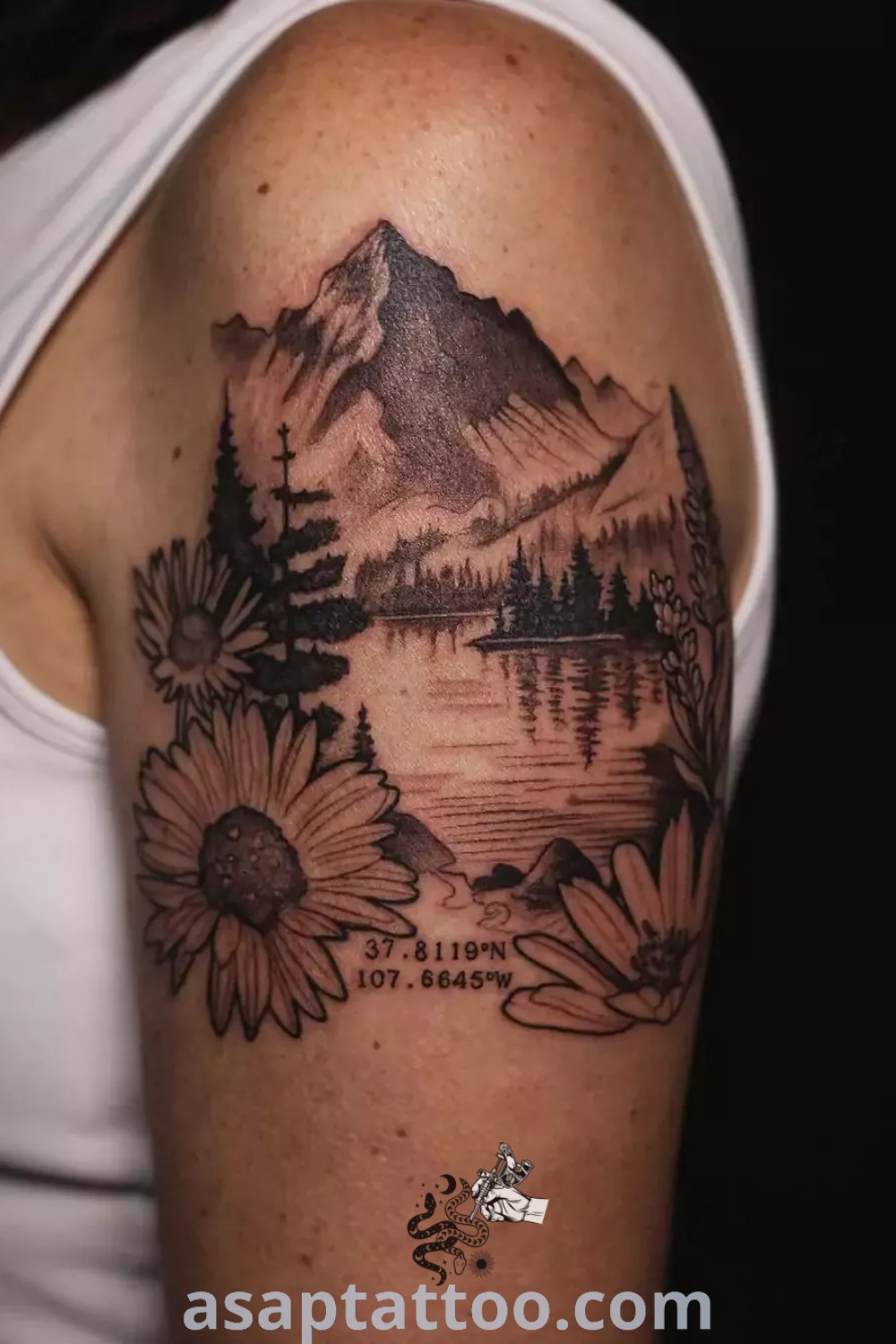 A woman showcasing a mountain and floral tattoo on her arm, featuring vibrant nature elements perfect for outdoor tattoos. A beautiful design that inspires tattoo lovers, discover more at asaptattoo.com.