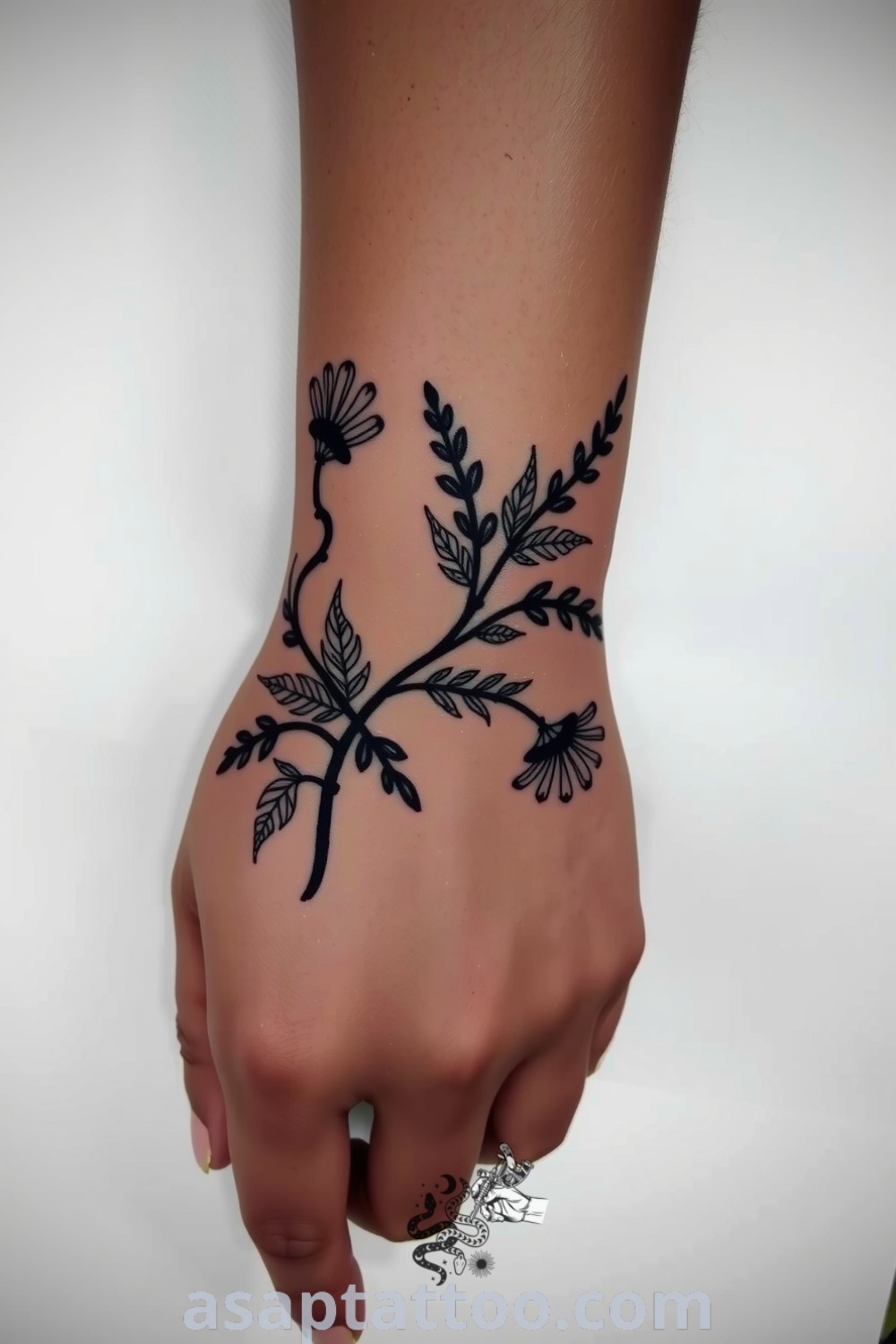 Elegant botanical wrist tattoo with intricate plants and vintage engravings, beautifully blending with dark skin. A gorgeous tattoo idea you must see to believe. asaptattoo.com
