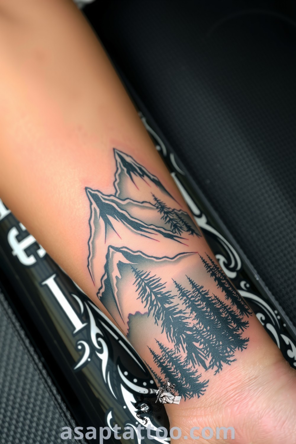Realistic tattoo of towering mountains and lush forest with intricate linework and earth tones, capturing the essence of nature. An amazing tattoo idea that you must see. asaptattoo.com
