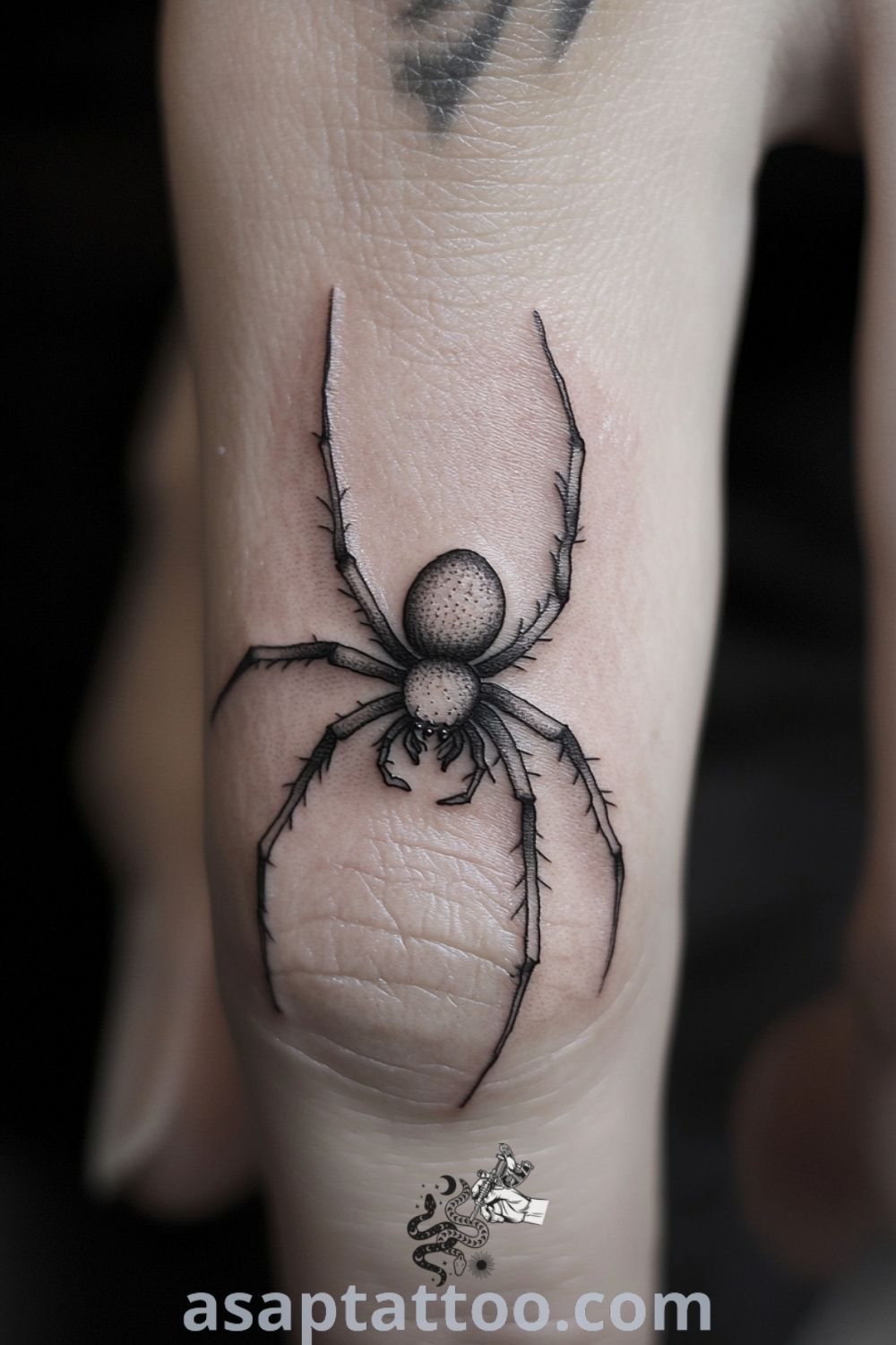 Delicate spider tattoo wrapping around a slender finger, featuring intricate details and contrasting black ink on light skin. A gorgeous tattoo idea that embodies strength and transformation. asaptattoo.com