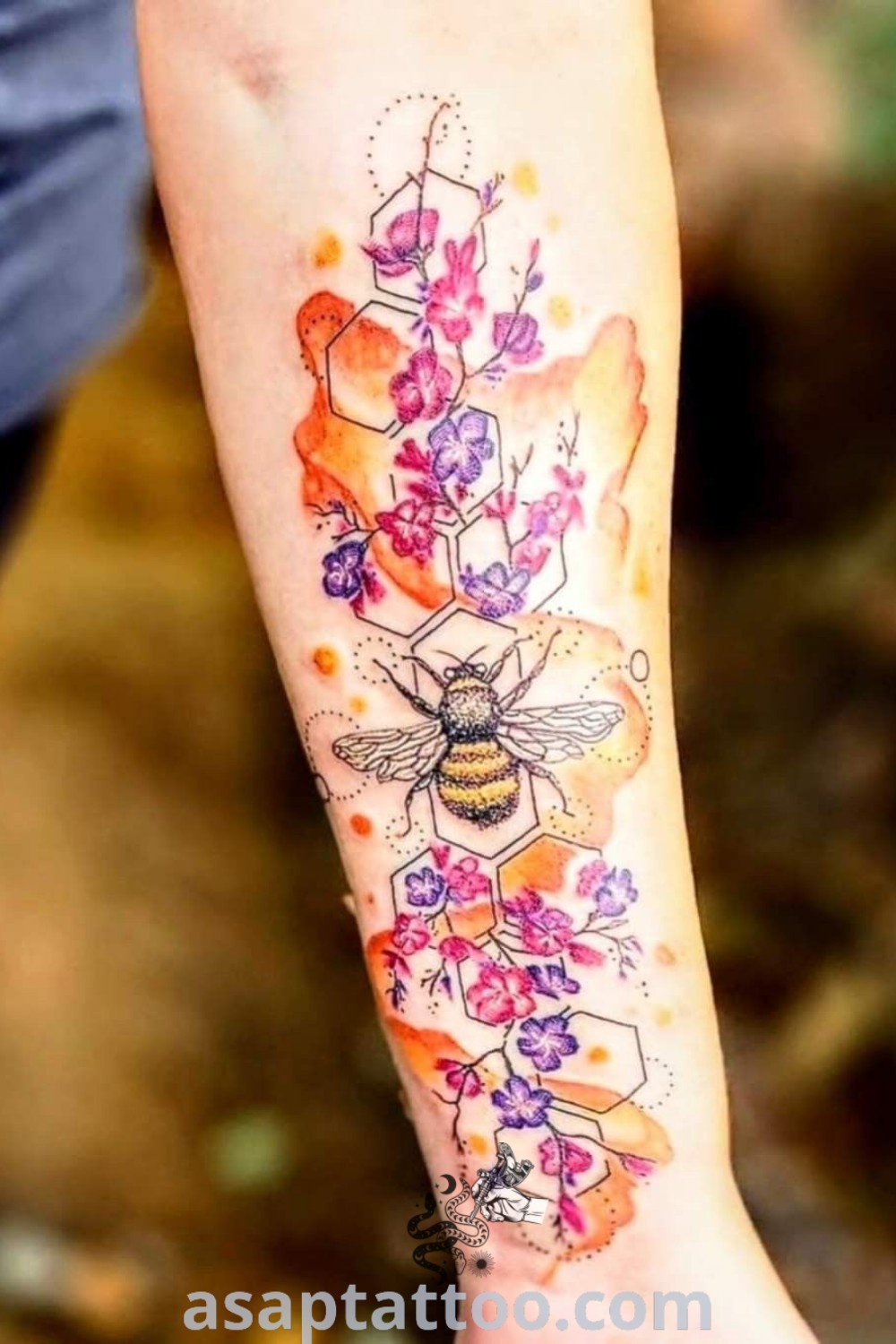 A person with a hibiscus and bee tattoo on their arm is holding a flower in front of them. This tattoo style combines floral and insect elements, showcasing aesthetic appeal and artistry. Visit asaptattoo.com for more best tattoo ideas.