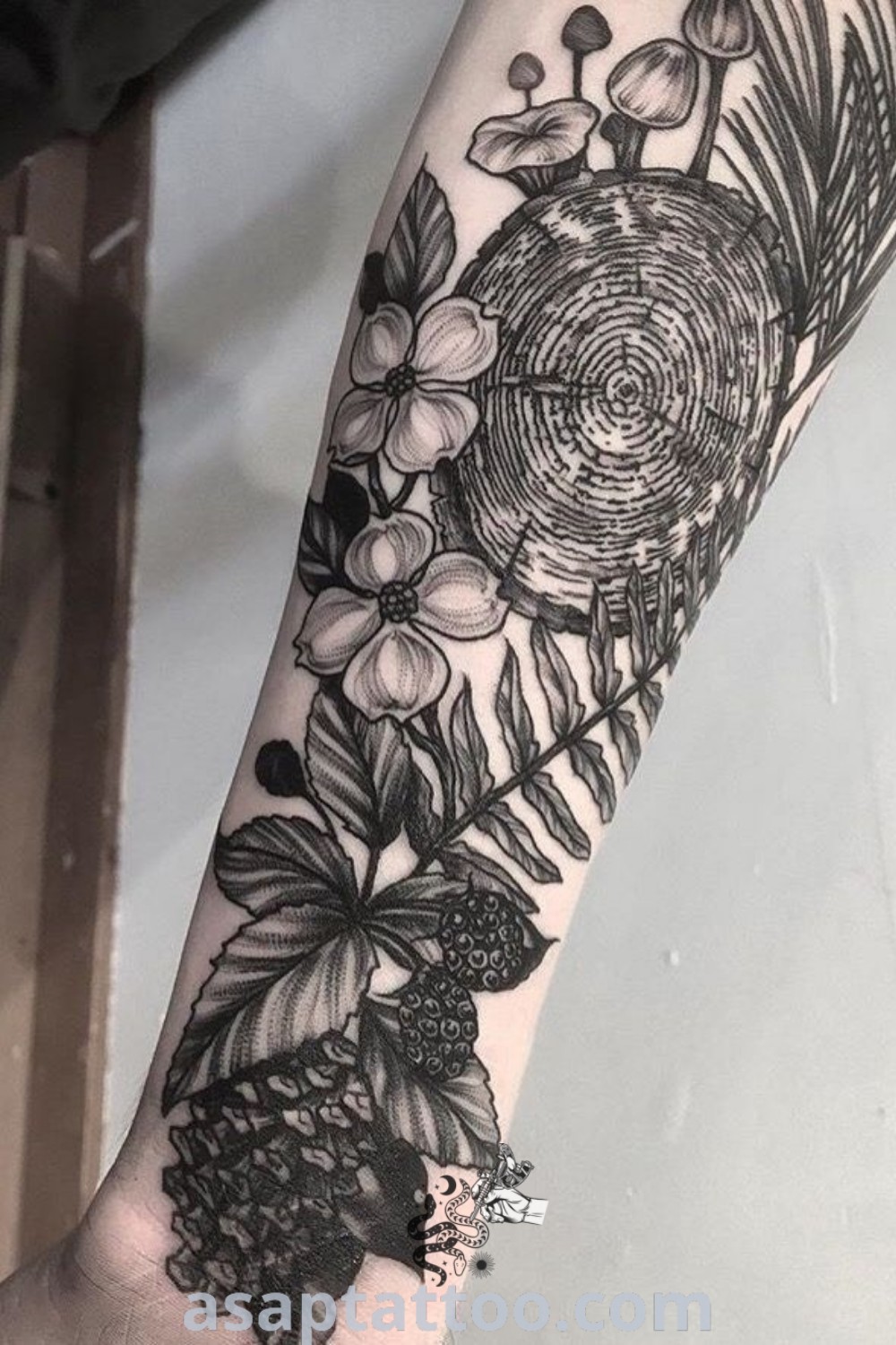Black and white flower tattoo on the left arm with pine cones, berries, and leaves, showcasing an elegant botanical design. This nature sleeve is perfect for those considering tattoos with meaning. Discover more ideas to inspire you at asaptattoo.com.