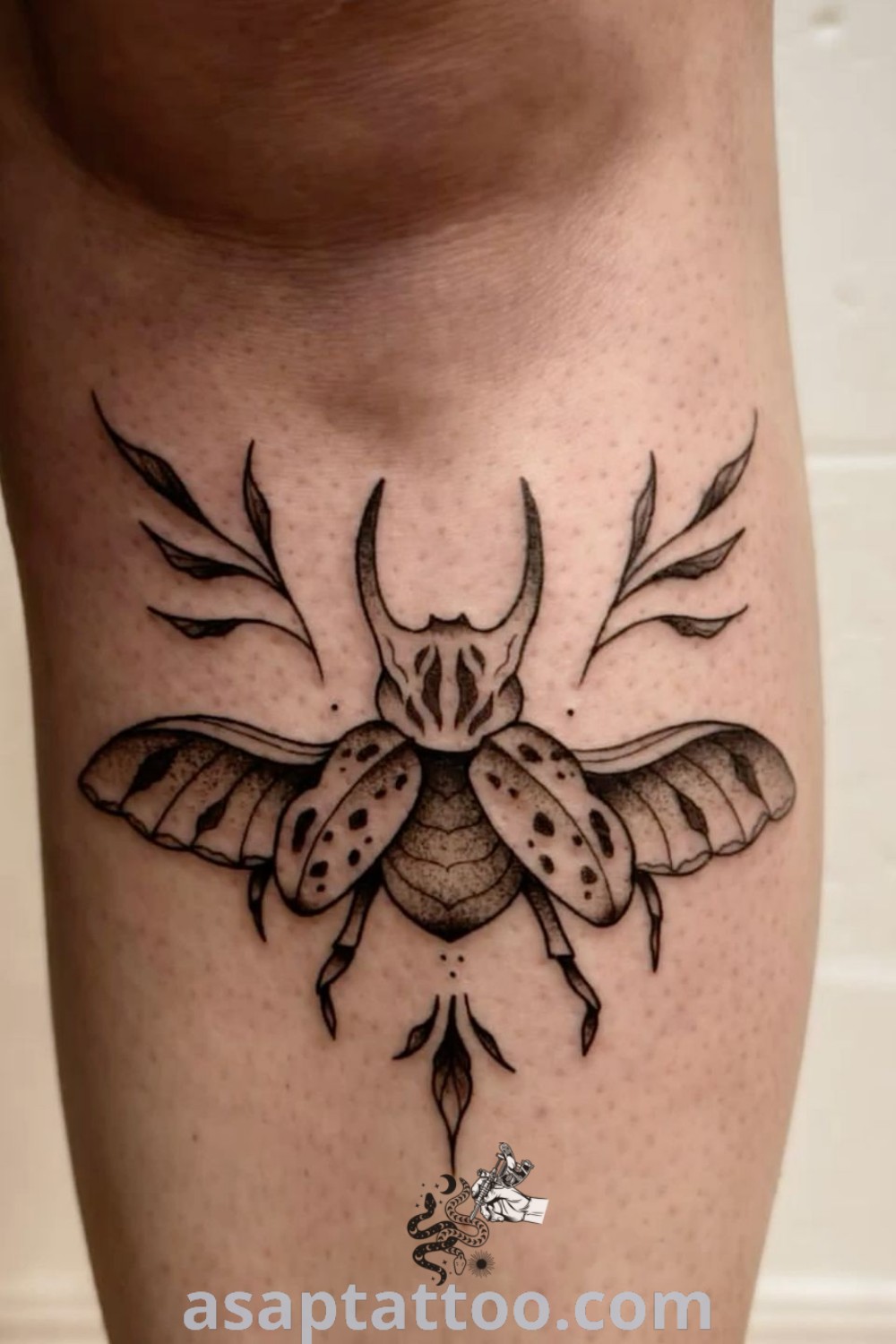 A tattoo on the leg featuring a horned beetle design surrounded by leaves, showcasing the best ideas for beetle tattoos. You will absolutely love these traditional and elegant designs at asaptattoo.com.