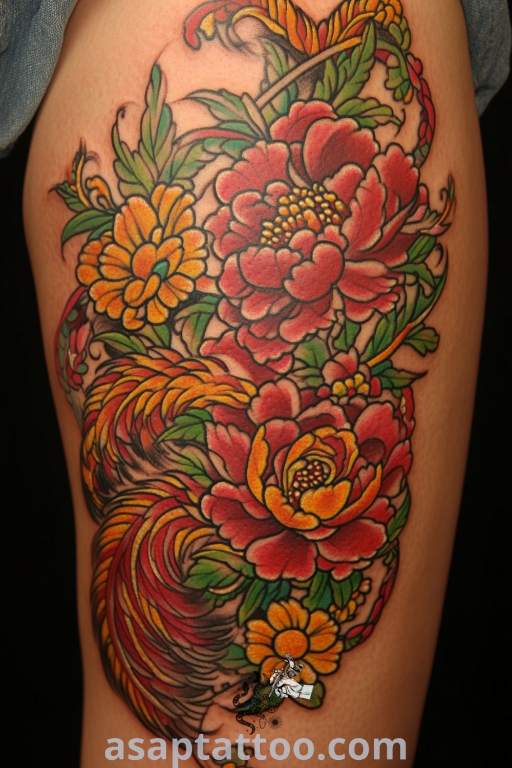 Floral phoenix tattoo on upper thigh featuring rich reds, yellows, and greens with intricate details and delicate linework. This gorgeous tattoo design inspires you to get inked and is one of the best tattoo ideas you have to see to believe. asaptattoo.com