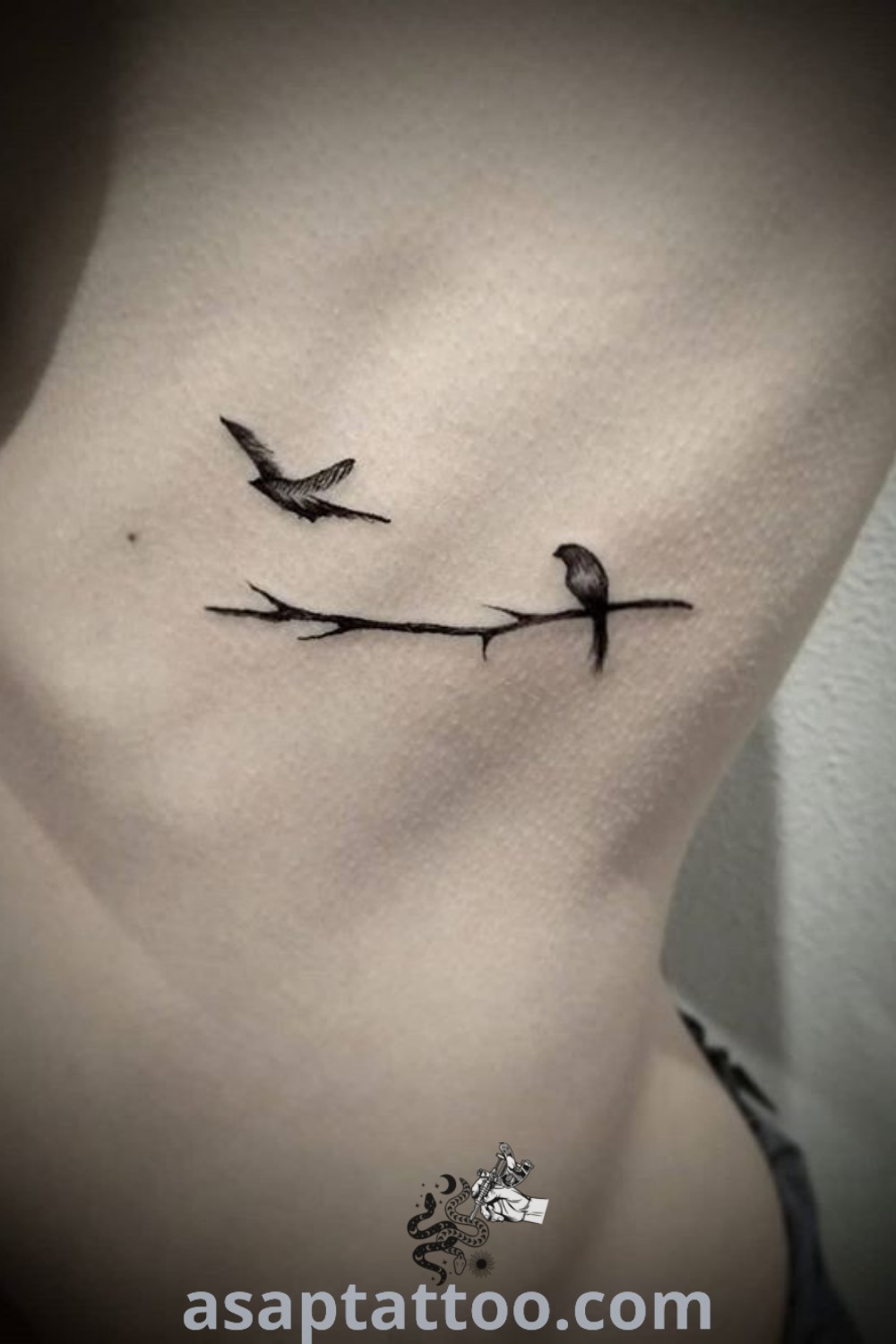 Charming bird and branch tattoo showcasing two birds sitting on a branch, ideal for a bird memorial tattoo or minimalist branch tattoo lovers. This artistic design represents beauty and meaning. For more amazing tattoo ideas, visit asaptattoo.com.