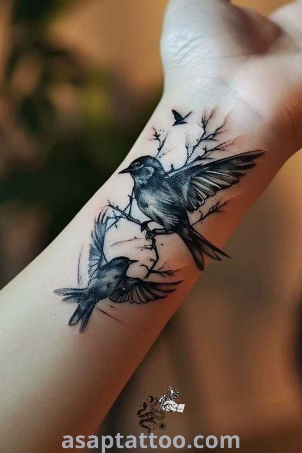 Elegant wren tattoo on wrist in black and grey ink with smaller flying birds, ideal for meaningful wrist tattoos. Perfect inspiration for tattoo lovers at asaptattoo.com.